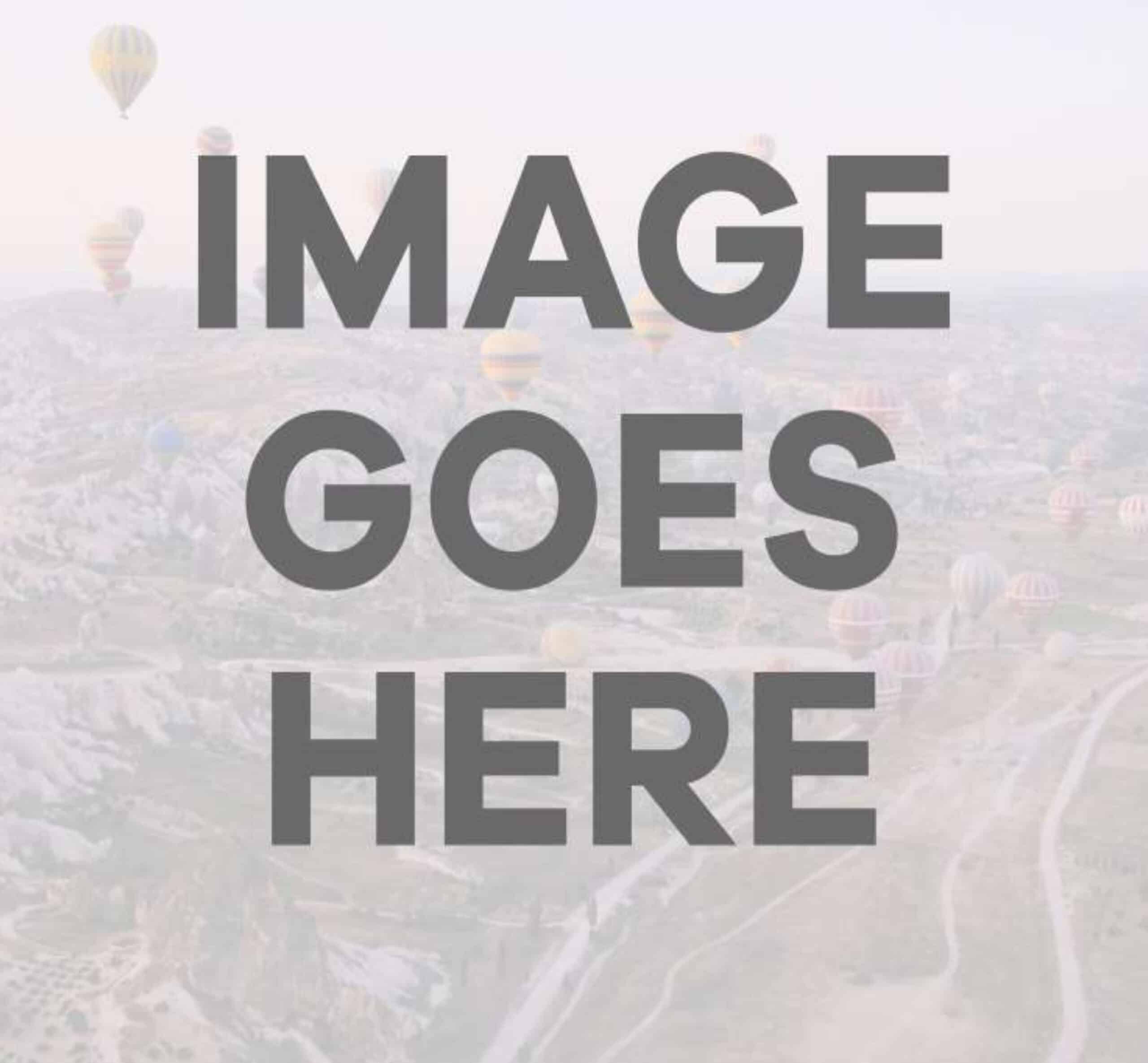 Hot air balloons floating above a misty valley landscape at dawn or sunrise.